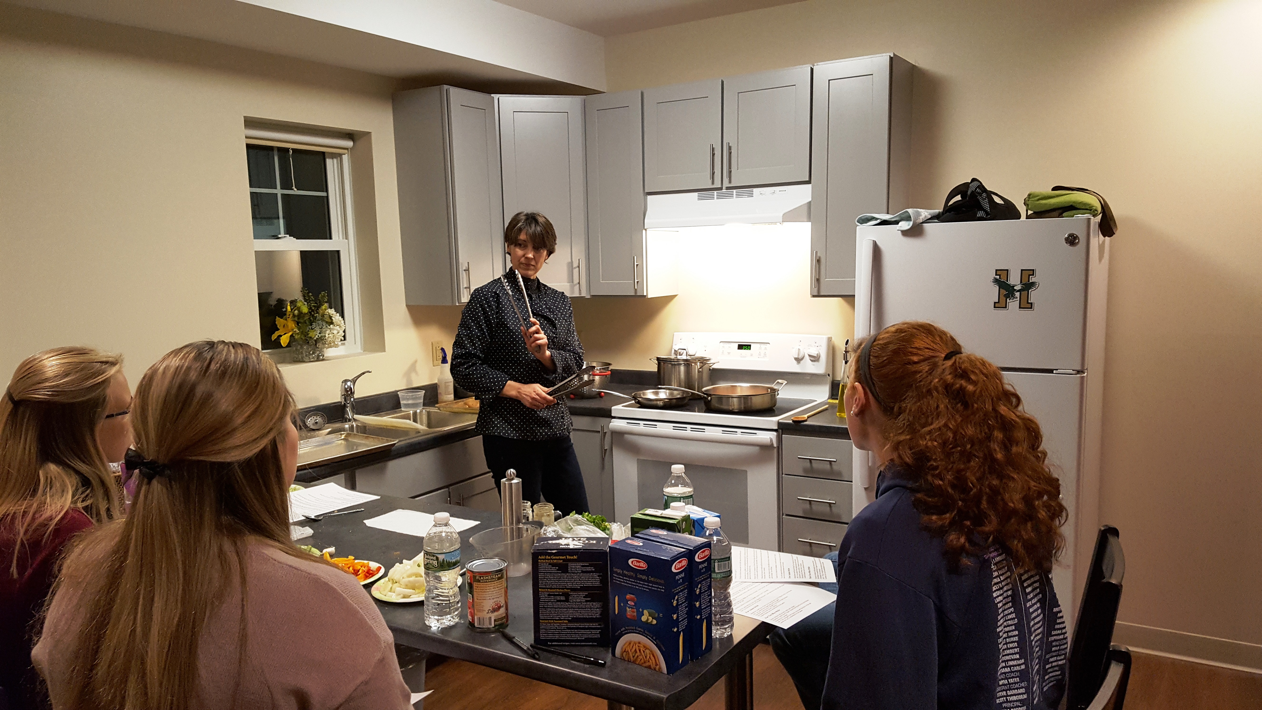 Students watch Cathy Speronis cook in the townhouse suites